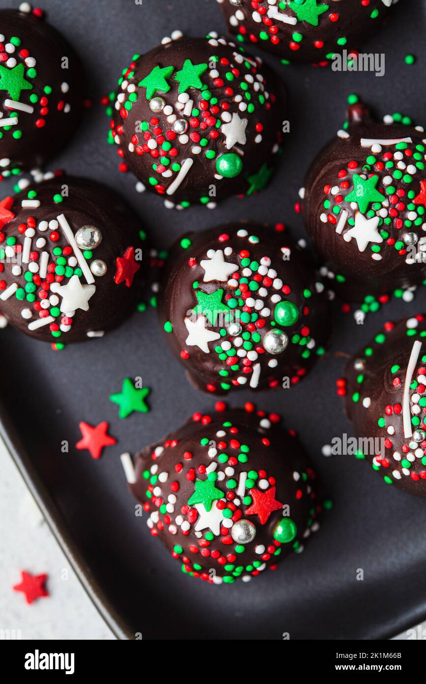 Weihnachten handgemachte Schokoladenkugeln mit Urlaub bestreut auf schwarzem Hintergrund. DIY Urlaub Kochen, Dessert Rezept. Stockfoto