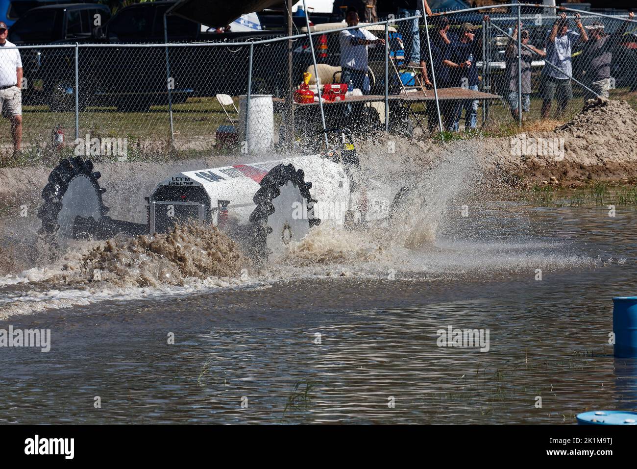 Sumpfbuggy, der sich durch das Wasser bewegt, Aktion, Nahaufnahme, Zuschauer hinter Kettengliederzaun, Wasserstrahl, Bewegung, Jeep-Stil, Fahrzeugsport, Florida Sports Stockfoto