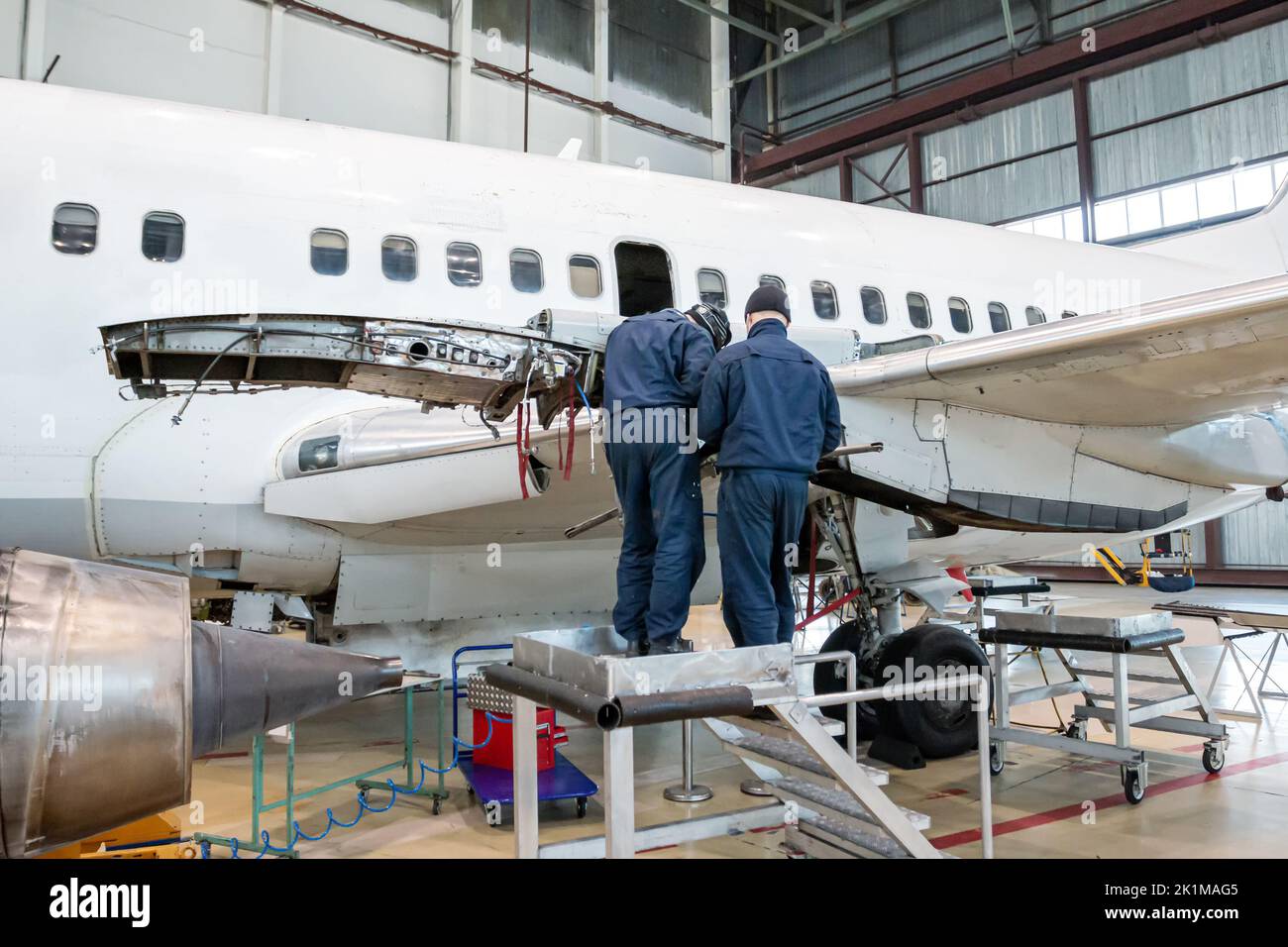 Weißes Passagierflugzeug im Hangar. Flugzeuge, die in Wartung sind. Vorbereitung der Motoraufhängung Stockfoto