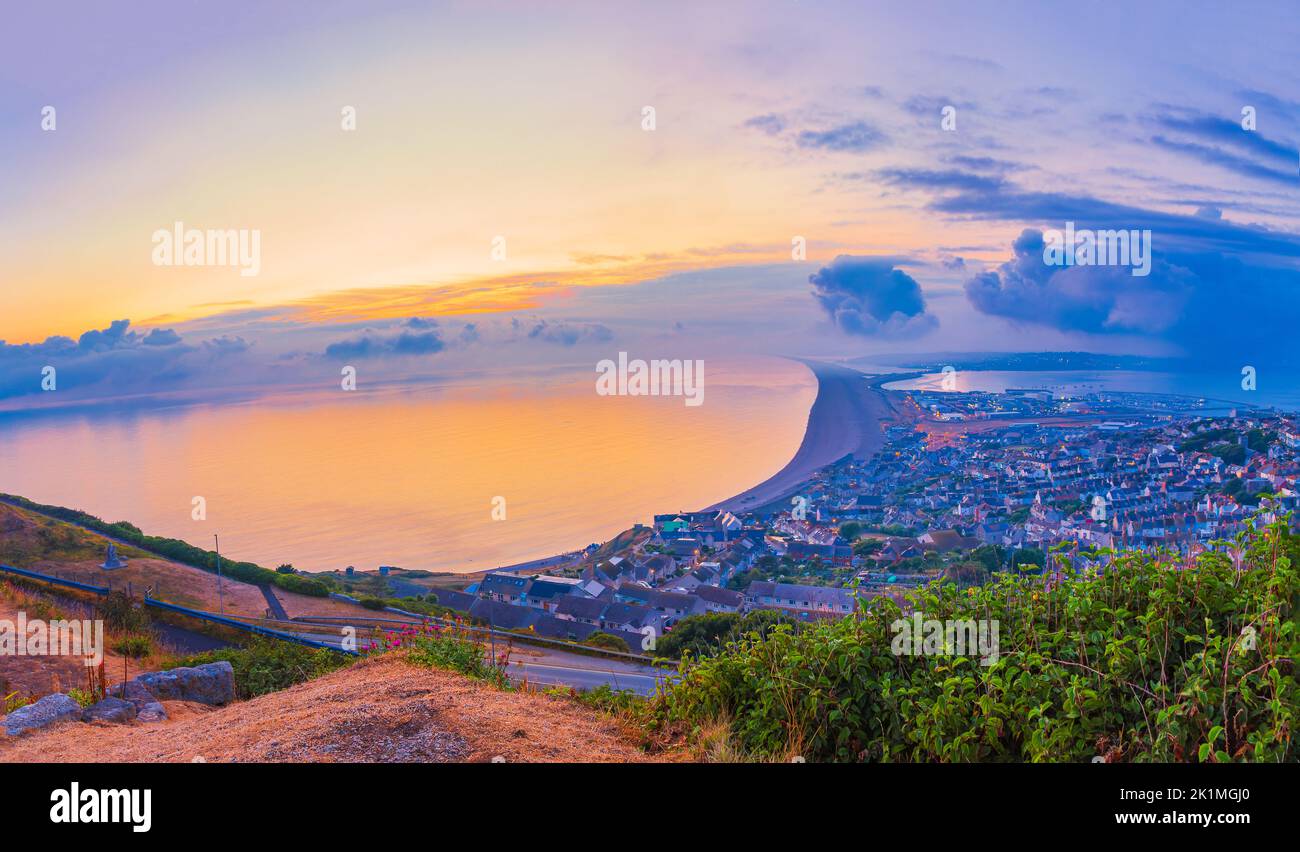 Atemberaubender Blick auf den Sonnenuntergang über dem chesil Beach auf der Isle of Portland an der Jurassic Coast von Dorset mit Blick zurück nach Weymouth Stockfoto