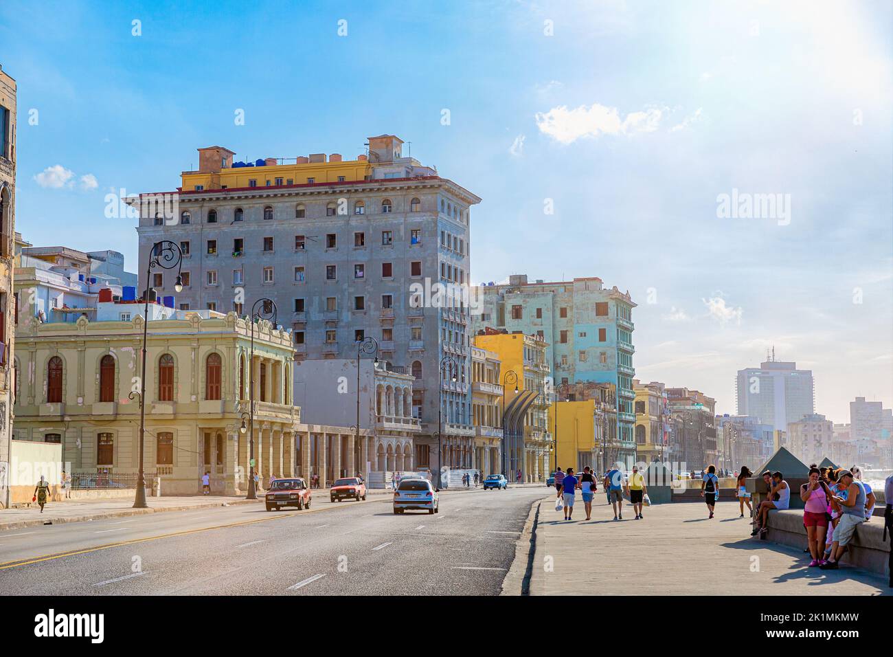 Eine Aufnahme der Promenade von El Malecon mit Menschen auf der Promenade neben einer Straße, auf der Autos fahren, und Gebäuden im Hintergrund Stockfoto