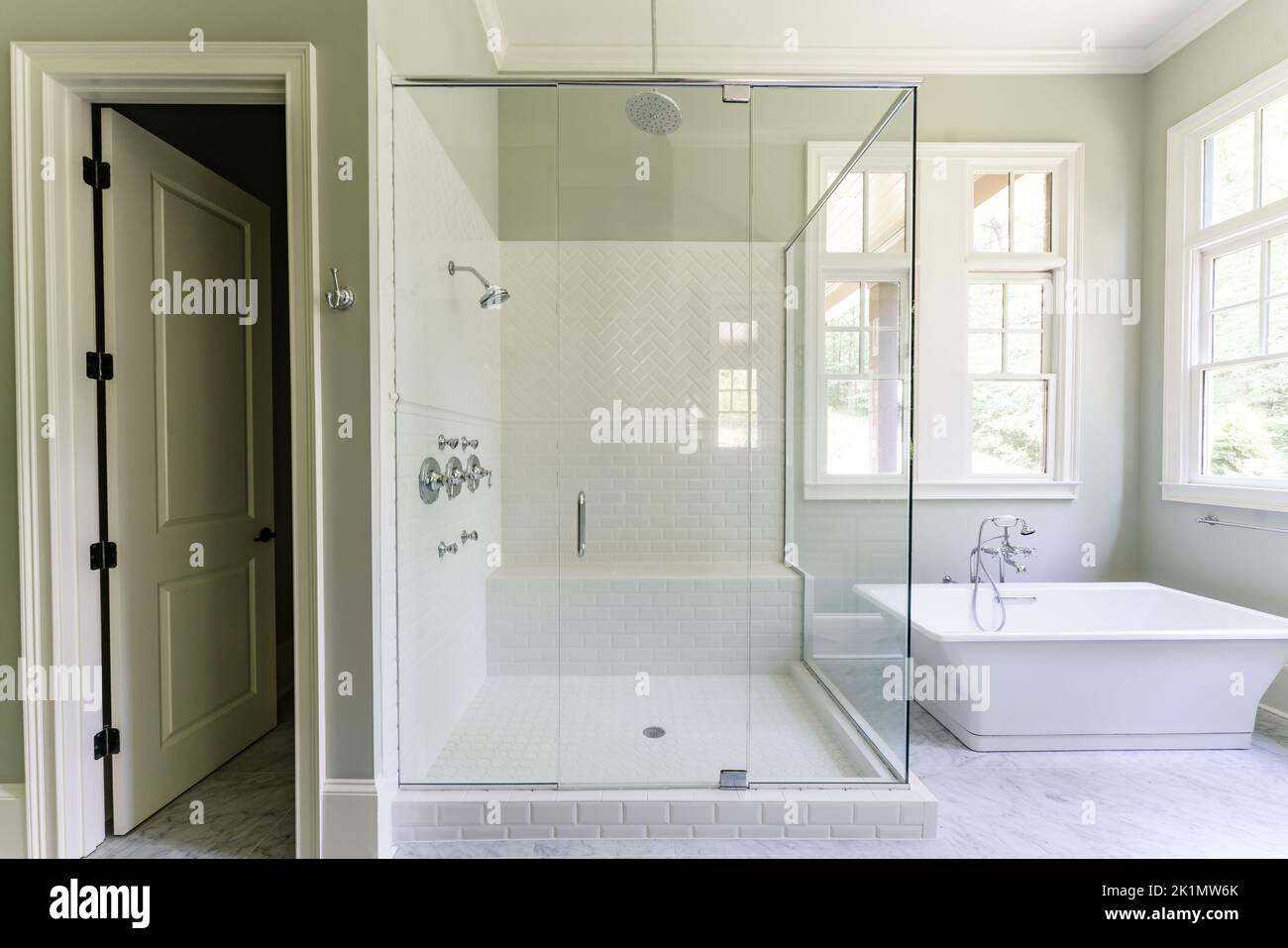 Bad in Salbeigrün mit weißen Decks, separater Badewanne, Dusche mit Glas mit Fischgrätstein, weiß gestrichen, Arbeitsplatte aus Granit Stockfoto