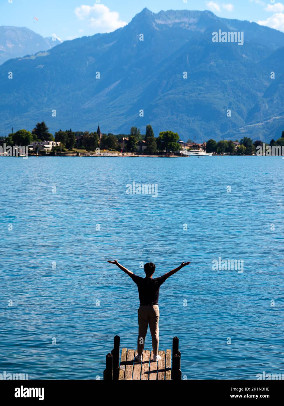 Ein Tourist mit ausgestreckten Armen am Pier des Genfer Sees Stockfoto