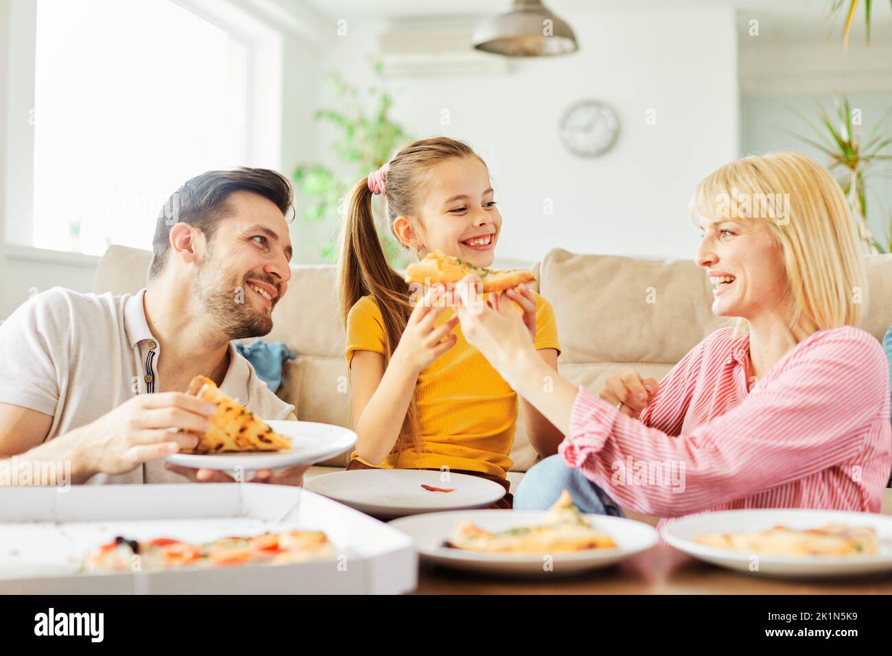 Pizza Familie Kind Essen zu Hause essen Tochter Mutter Vater glückliches Essen zusammen Mittagessen Abendessen Mann Frau Mädchen Spaß Stockfoto