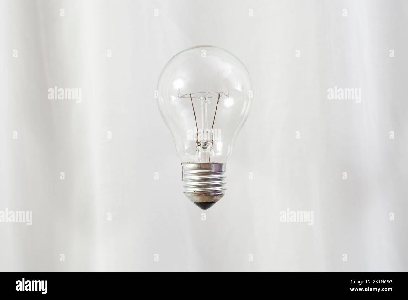 Transparente Glühbirne schweben auf weißen Vorhängen Hintergrund. Stockfoto