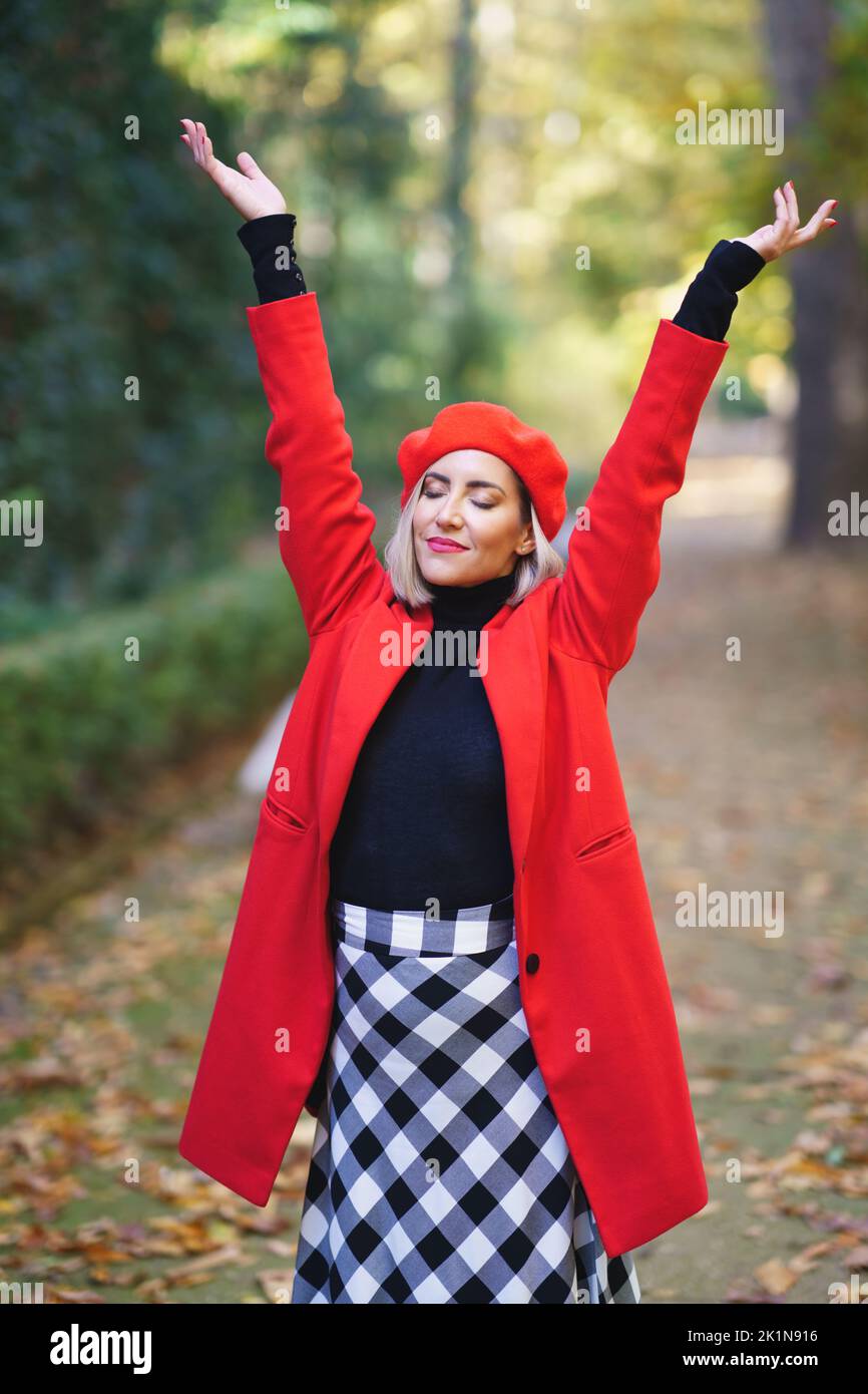 Content Frau mit erhobenen Armen im Herbstpark Stockfoto