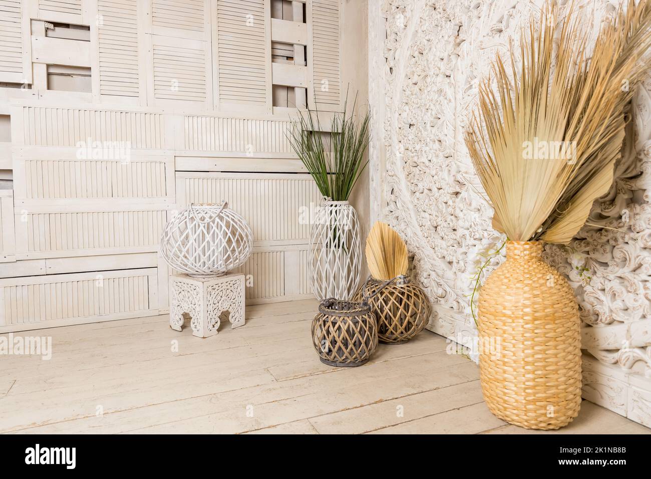 Stilvolles Konzept der Wohnzimmereinrichtung mit getrocknetem Blatt in Vase, Rattan-Körben, Pflanze, Holzwand und persönlichen Accessoires in Home decor.hygge Stockfoto