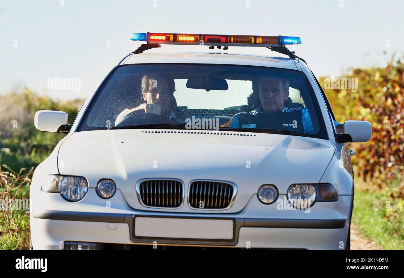 Sie sind auf der Suche. Ein Polizeiauto patrouilliert auf einer Landstraße. Stockfoto