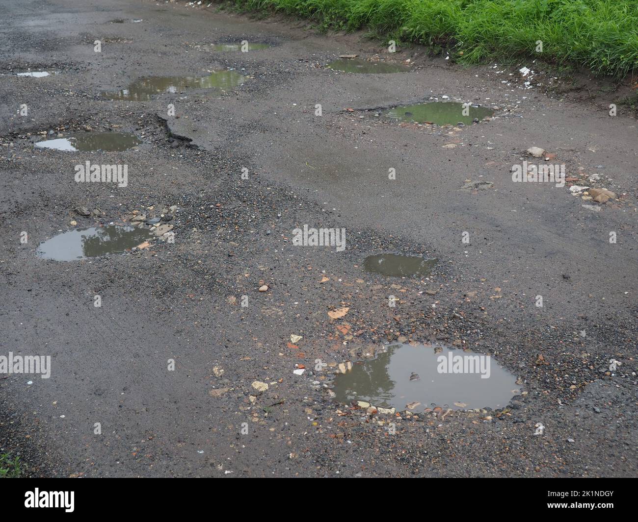 Löcher auf einer mit Wasser gefüllten Feldstraße Stockfoto