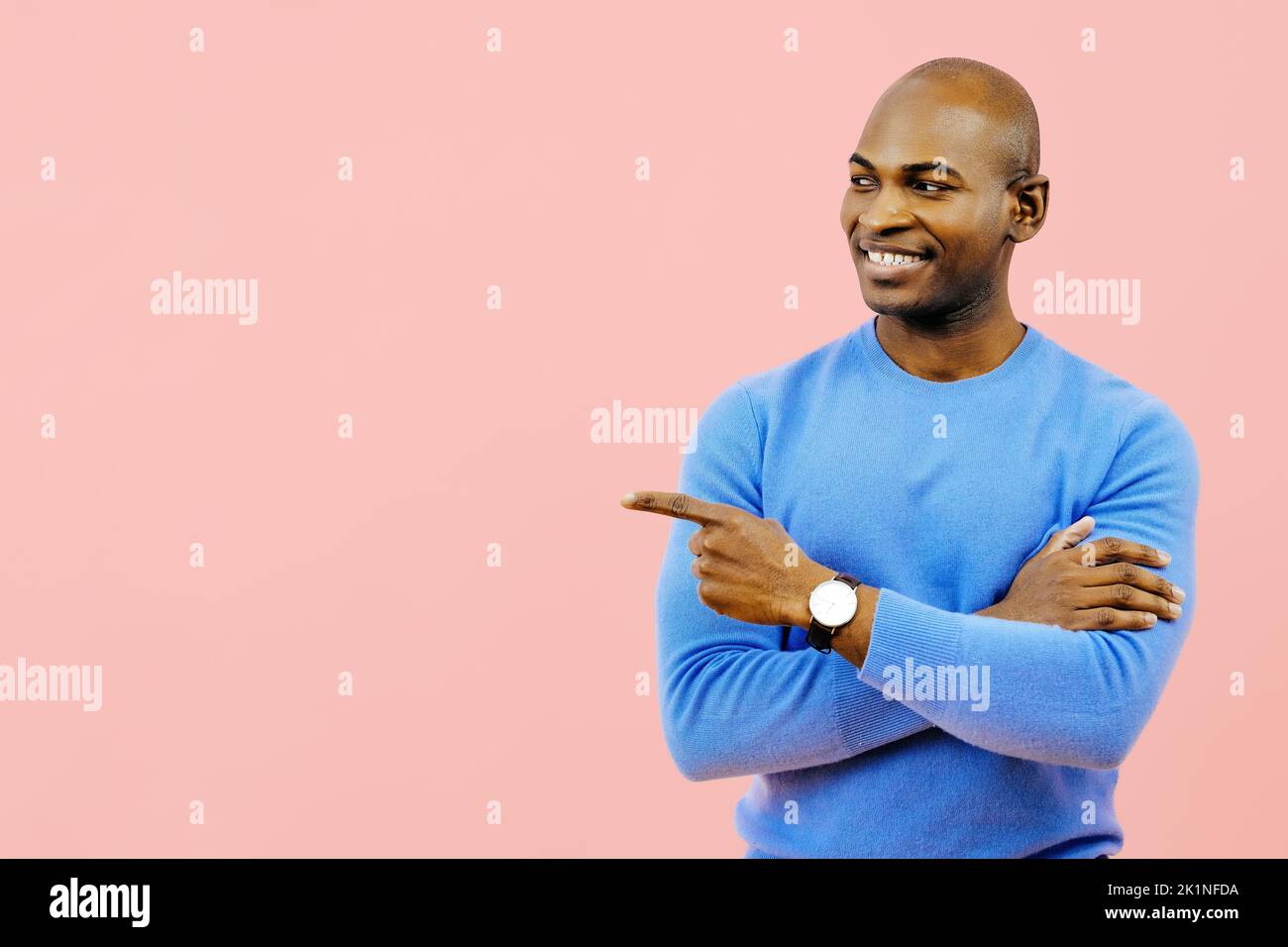 Lächelnder Mann mit gefalteten Armen, der auf den Kopierraum im Studio zeigt Stockfoto