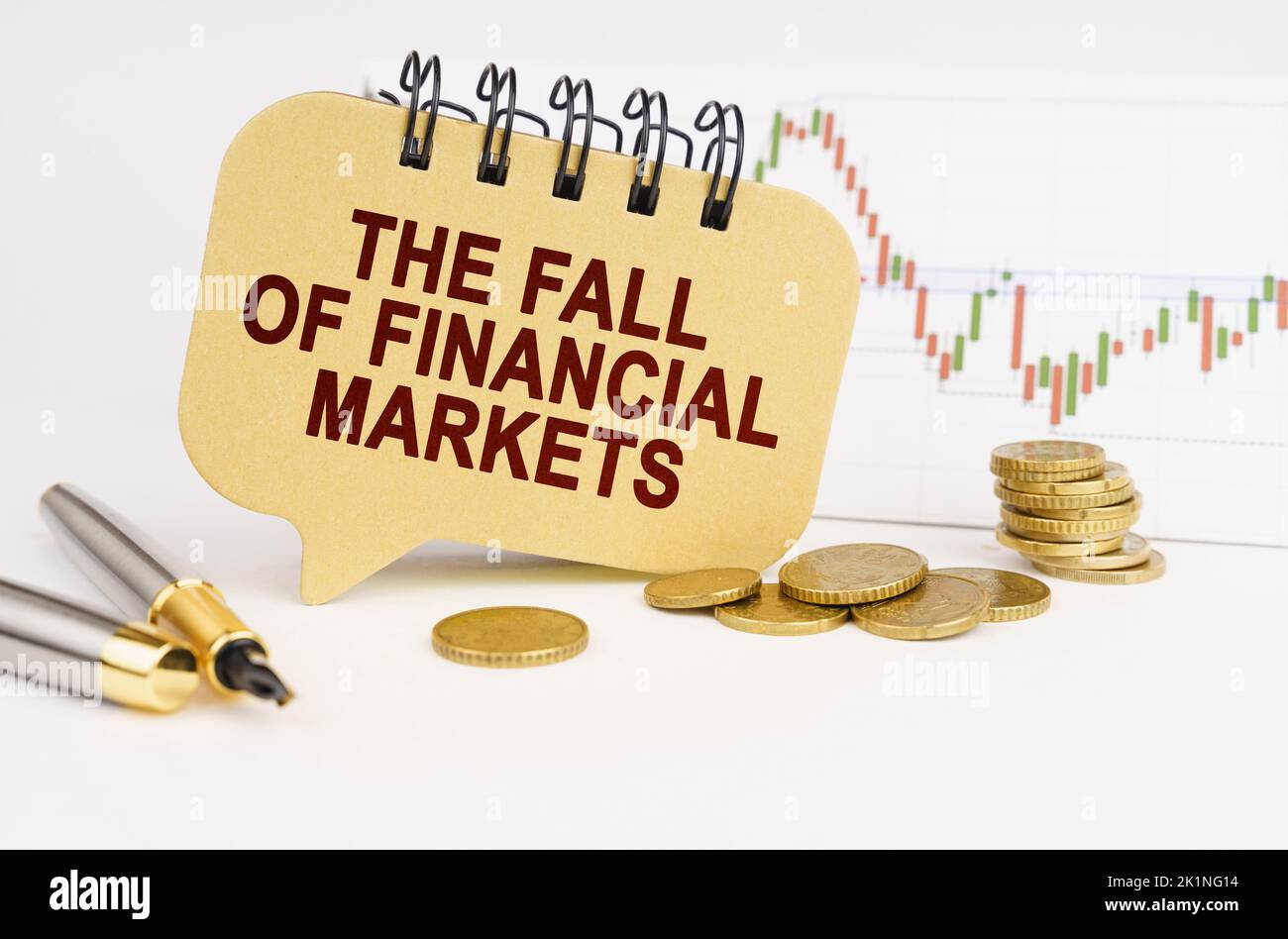 Geschäftskonzept. Auf dem Tisch sind Münzen, ein Stift, eine Grafik und ein Schild mit der Aufschrift - der Fall der Finanzmärkte Stockfoto