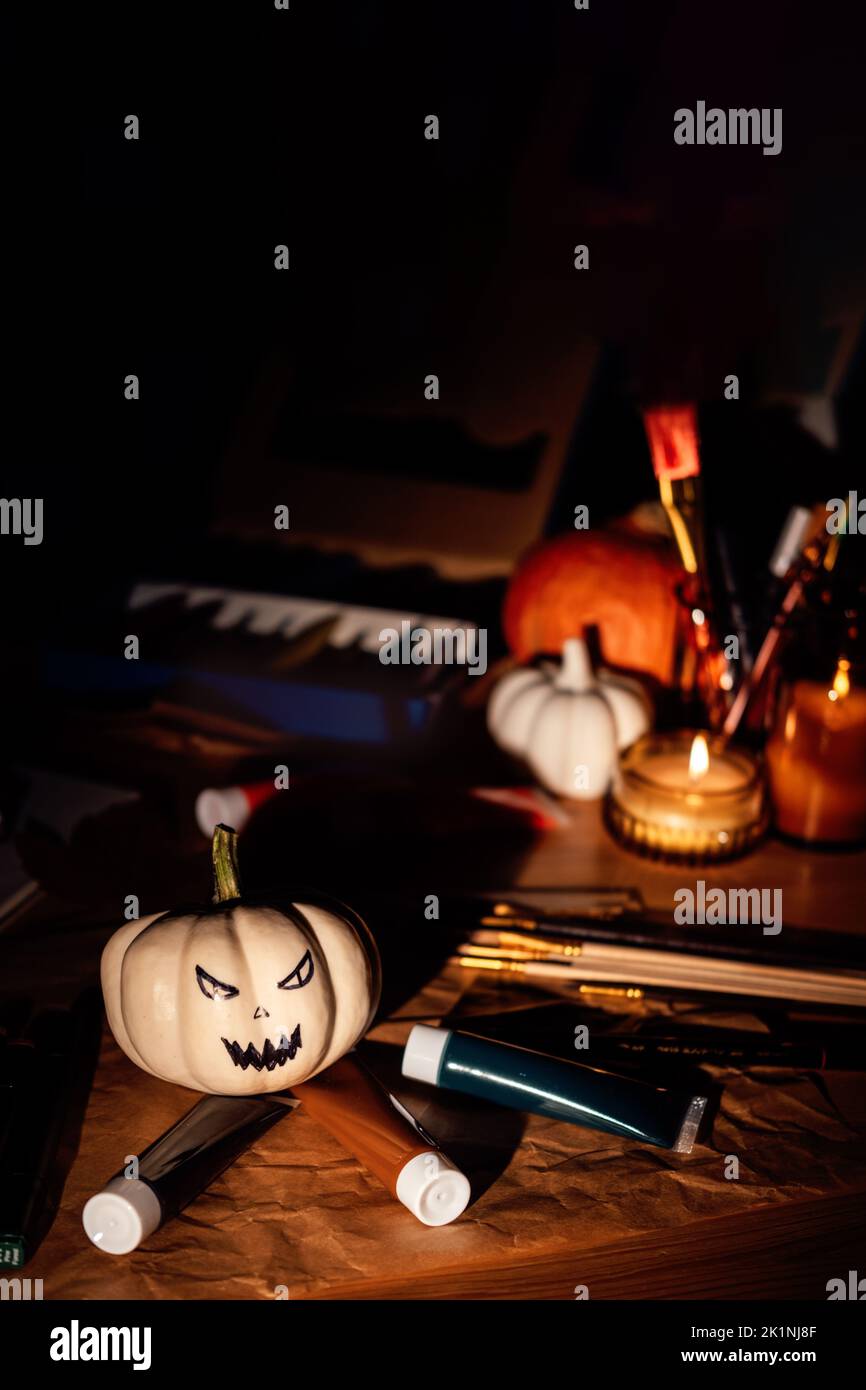 Halloween Kunst und Kunsthandwerk. In dunkler Nacht Kürbisse, Pinsel und Farben auf dem Tisch malen. Nahaufnahme des bemalten Kürbisses für Halloween. Stockfoto