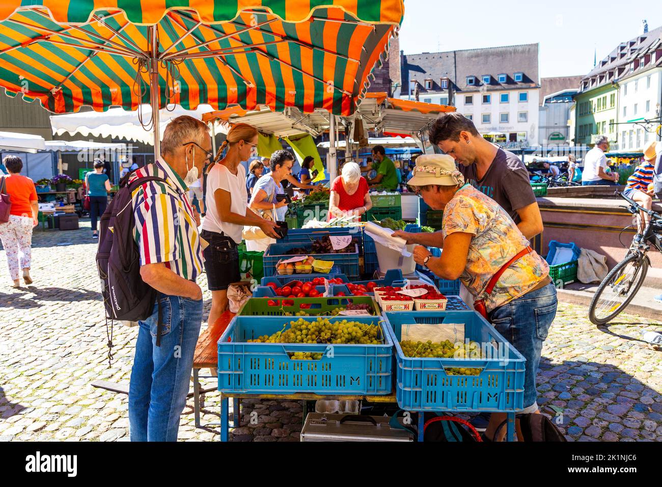 Menschen, die an einem Obst- und Gemüsestandard am Münstermarkt auf dem Münsterplatz, Freiburg im Breisgau, einkaufen Stockfoto