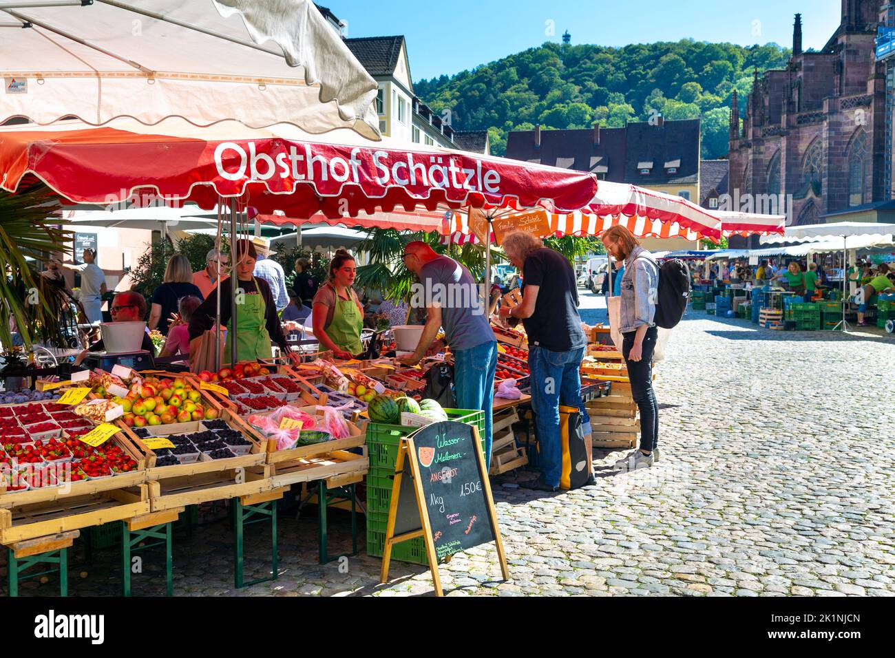 Menschen, die an einem Obst- und Gemüsestandard am Münstermarkt auf dem Münsterplatz, Freiburg im Breisgau, einkaufen Stockfoto