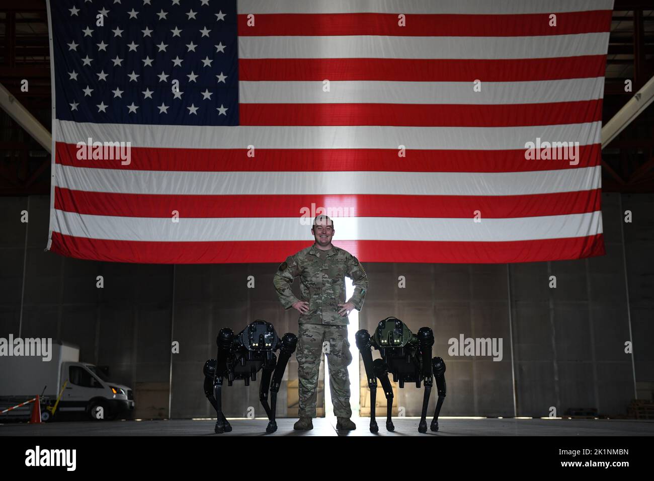 Cape Canaveral, Vereinigte Staaten von Amerika. 28. Juli 2022. US Air Force Tech Sgt. Brandon Priddy, 45. Security Forces Squadron Officer verantwortlich für Innovation und Technologie stellt sich mit zwei Ghost Robotics Quadruped Vision 60 unbemannte Bodenfahrzeuge, bekannt als Roboterhunde, vor einer amerikanischen Flagge auf der Cape Canaveral Space Force Station, 27. Juli 2022 in Cape Canaveral, Florida. Quelle: SRA Samuel Becker/US Space Force Photo/Alamy Live News Stockfoto