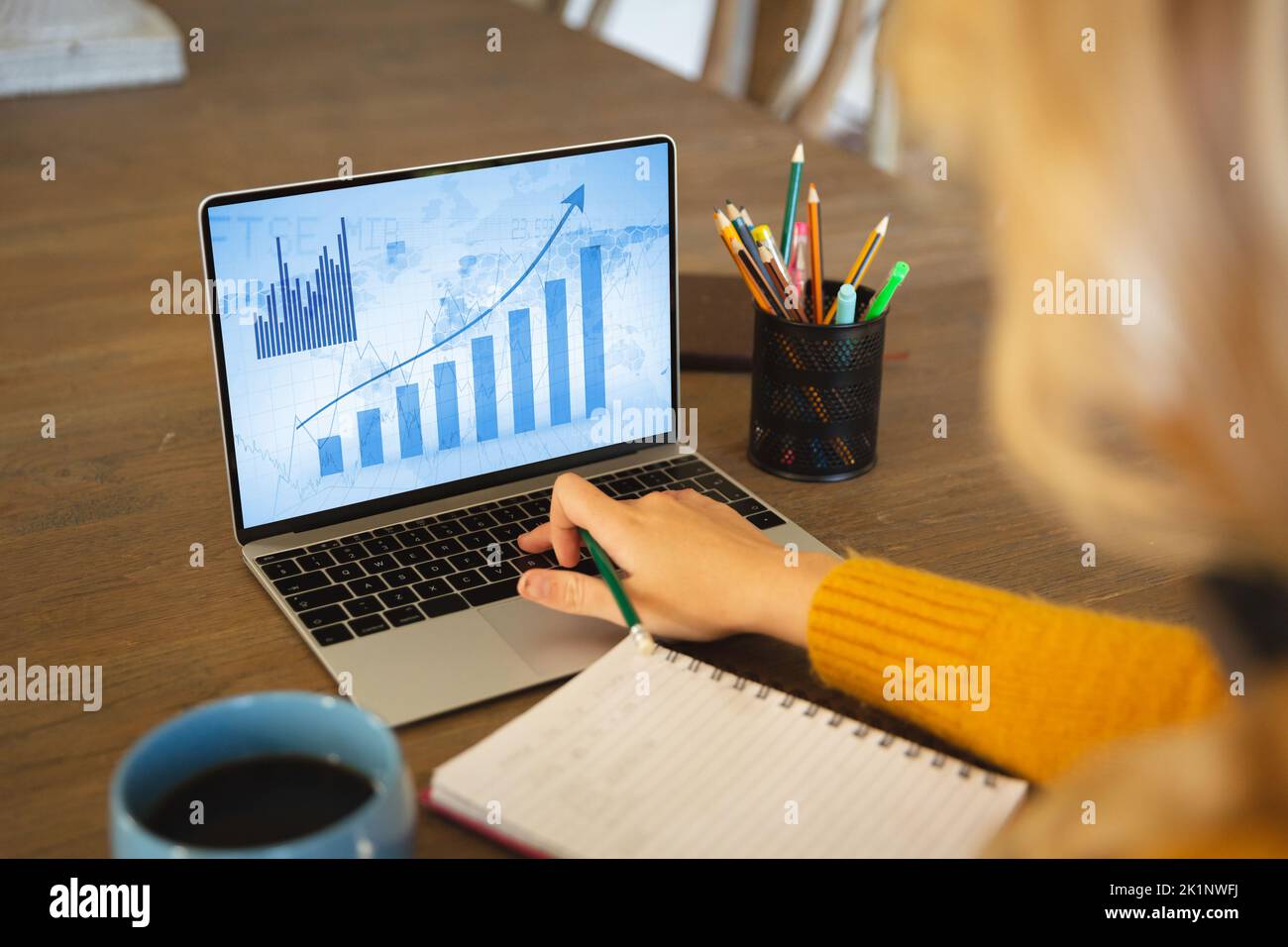 Die kurze Hand des kaukasischen Unternehmers, der im Büro Geschäftsdiagramme über einem Laptop analysiert Stockfoto