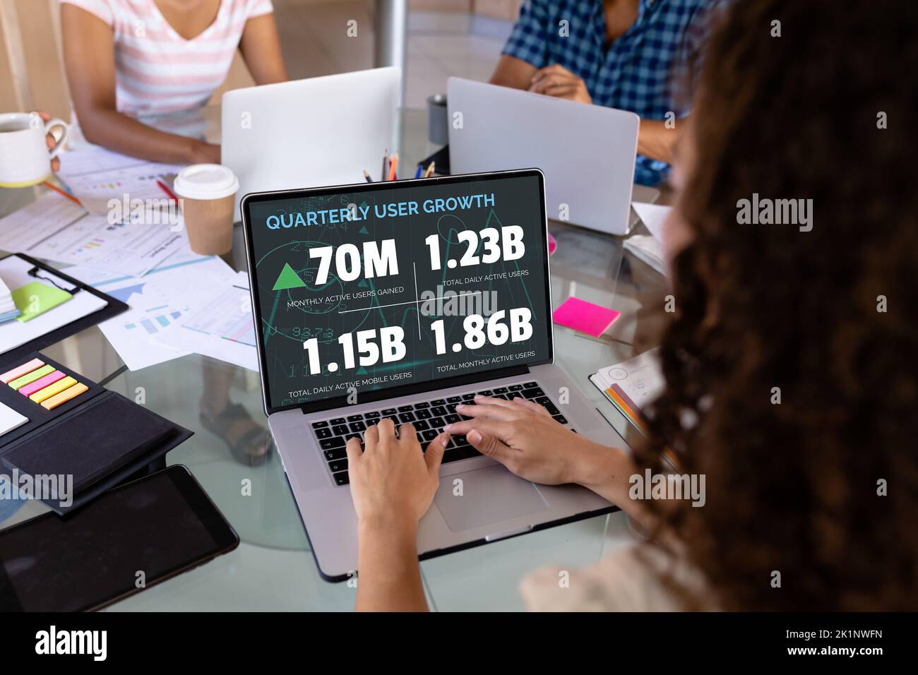 Rückansicht einer kaukasischen Geschäftsfrau, die den Quartalsbericht über einen Laptop auf dem Schreibtisch im Büro analysiert hat Stockfoto