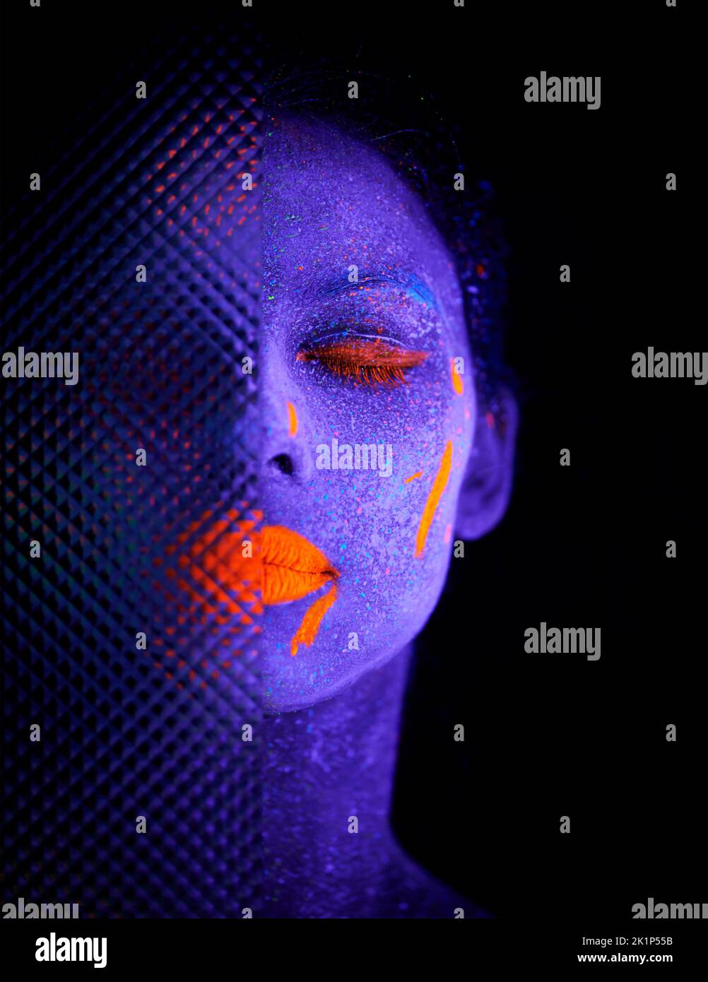 Lassen Sie Ihre Fantasie zum Leben erwecken. Eine junge Frau posiert mit Neonfarbe auf ihrem Gesicht. Stockfoto