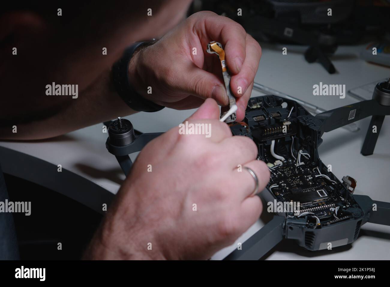Nahaufnahme der Hände von mans, die eine Drohne auf einem weißen Tisch mit verschiedenen Werkzeugen reparieren Stockfoto