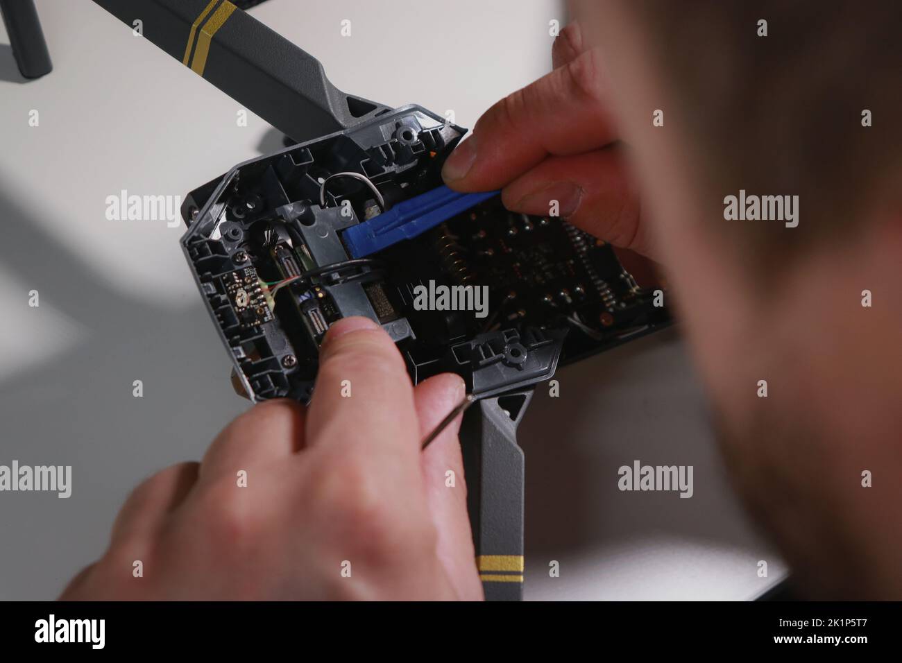 Nahaufnahme der Hände von mans, die eine Drohne auf einem weißen Tisch mit verschiedenen Werkzeugen reparieren Stockfoto