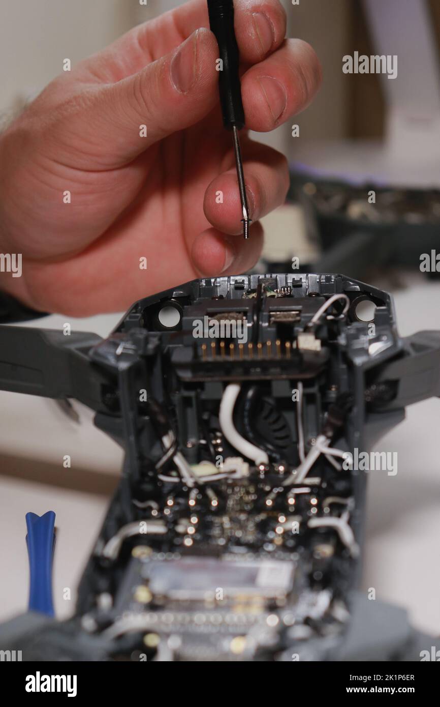 Nahaufnahme der Hände von mans, die eine Drohne auf einem weißen Tisch mit verschiedenen Werkzeugen reparieren Stockfoto