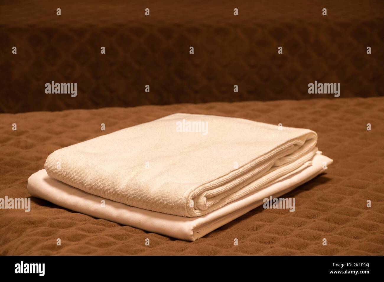 Einzelbett mit weißen Handtüchern im Schlafzimmer im Appartementgebäude, Schlafzimmermöbel, Bett und braunes Karo Stockfoto
