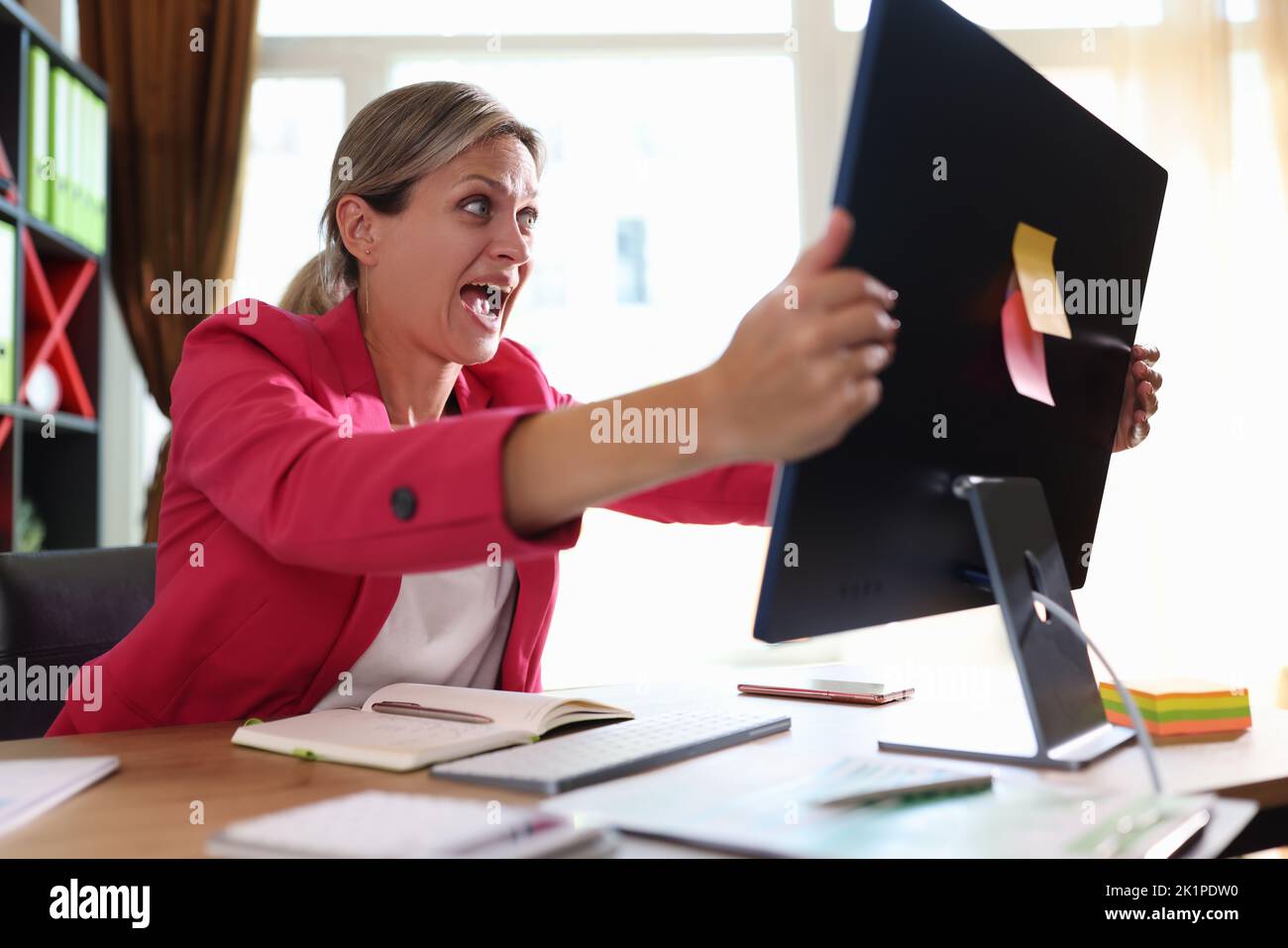Geschäftsfrau schreit hysterisch auf Computermonitor im Büro Stockfoto