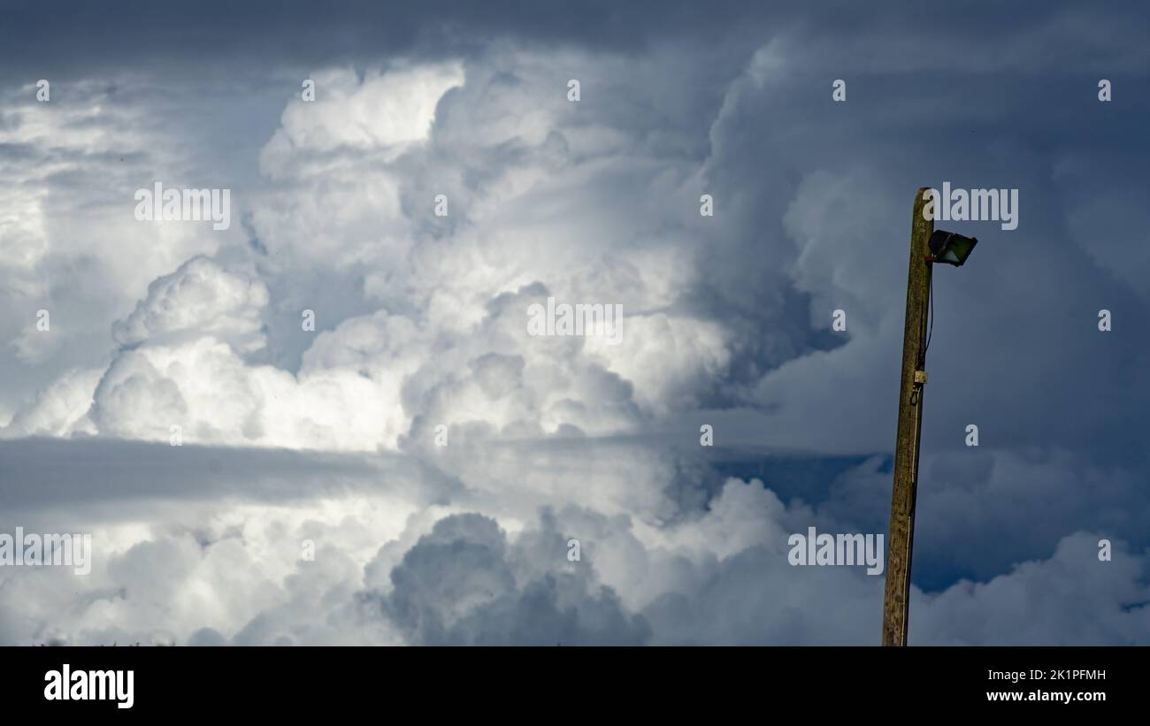 Gewitterwolken füllen den Himmel hinter einem alten Laternenpfahl Stockfoto
