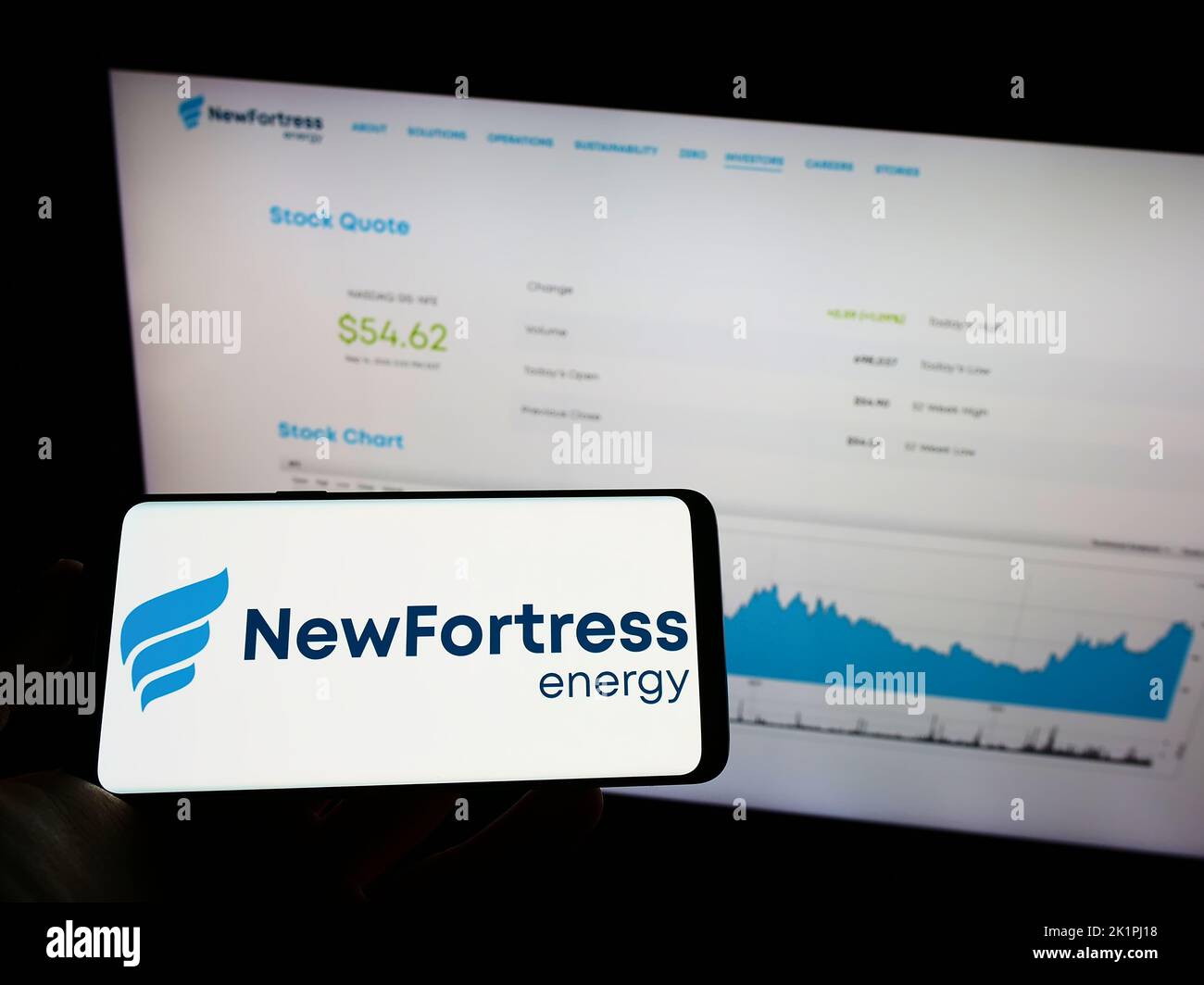 Person, die Mobiltelefon mit dem Logo der US-Firma New Fortress Energy Inc. Auf dem Bildschirm vor der Business-Webseite hält. Konzentrieren Sie sich auf die Telefonanzeige. Stockfoto