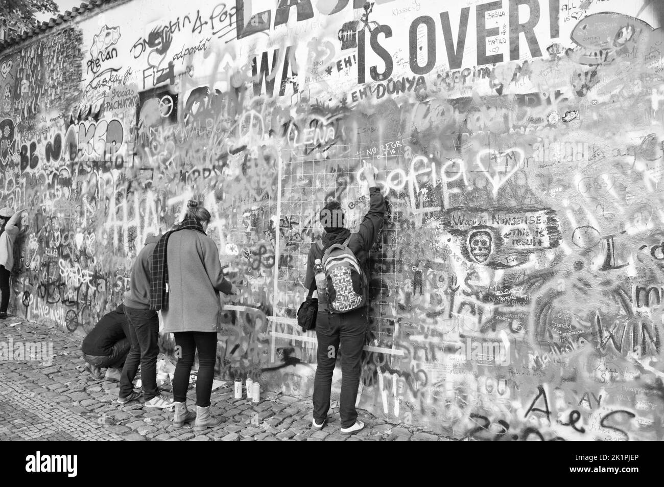 Eine Gruppe junger Menschen malt ein Graffiti auf die John-Lennon-Mauer in Prag, Tschechien Stockfoto