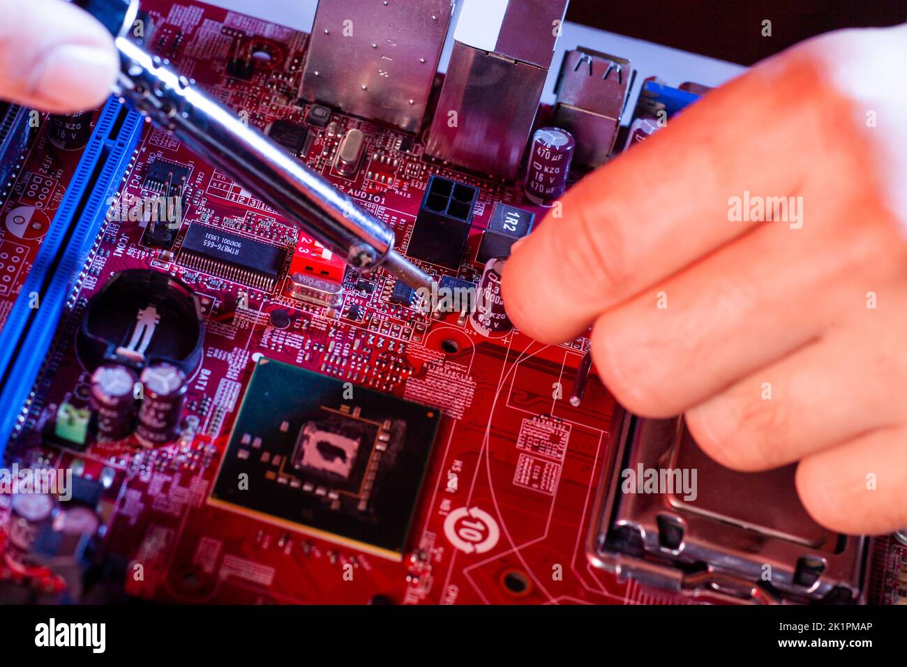 Ein Mann, der ein Motherboard lötet. Reparatur und Wartung von Desktop-PCs und Laptops. Stockfoto