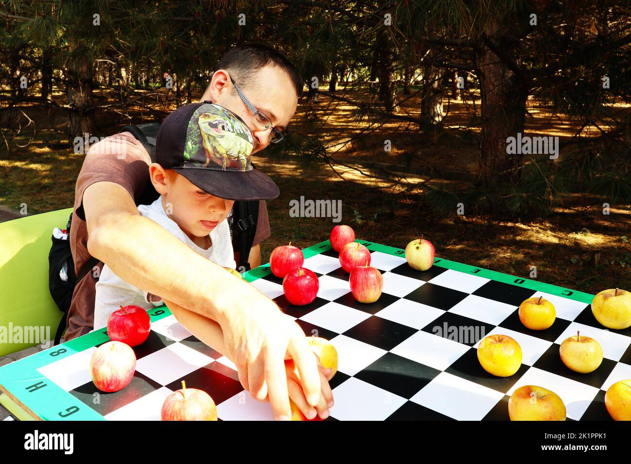 Vater und Sohn spielen Steine mit roten und grünen Äpfeln Stockfoto