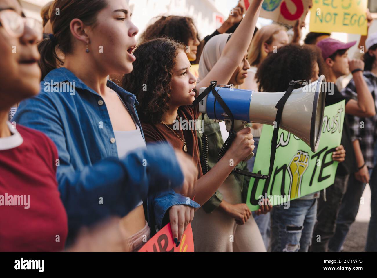 Verschiedene junge Menschen marschieren mit Transparenten und einem Megaphon für Klimagerechtigkeit. Gruppe multikultureller Jugendaktivisten, die gegen globale Warmi protestieren Stockfoto