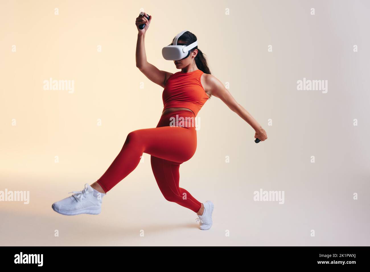 Energische junge Frau, die mit 3D-Technologie arbeitet. Sportliche junge Frau, die ein Virtual-Reality-Fitnessspiel erkundet. Athletische junge Frau, die Kunstgegenstände trägt Stockfoto