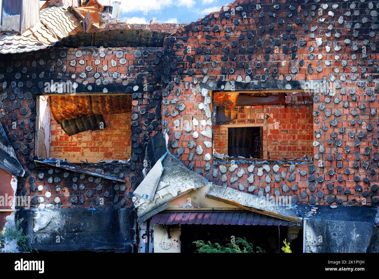 Leere Fensterbuchsen eines ausgebrannten Landhauses nach einem Raketenangriff russischer Besatzer eines ukrainischen Dorfes. Stockfoto