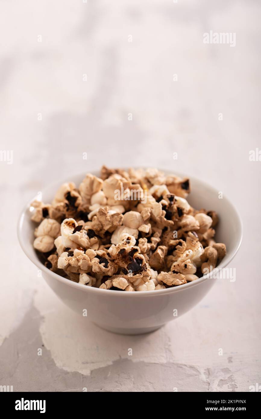 In der kleinen weißen Schüssel auf Keramik verbranntes Popcorn Stockfoto