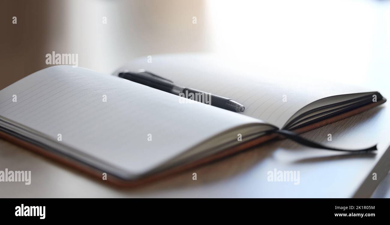 Büromockup-Notizbuch und -Stift auf einem Schreibtisch zum Arbeiten, Schreiben oder Planen eines Zeitplans. Professionelles, leeres und isoliertes Texturbuch, Tagebuch oder Notizblock Stockfoto