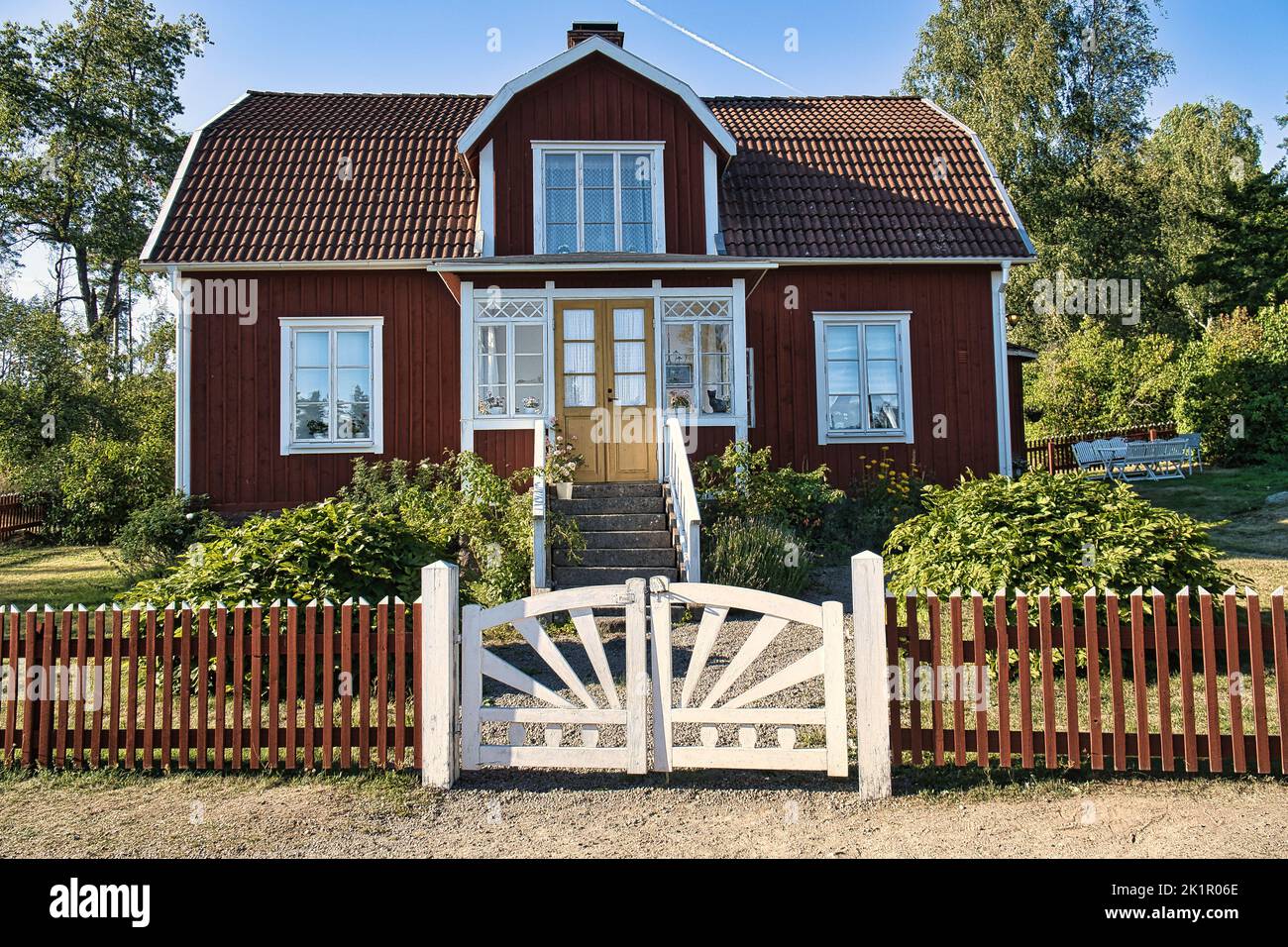 Schwedisches rot-weißes traditionelles Haus in Smalland, weißer Zaun grüner Garten blauer Himmel. Kindheitserinnerungen aus dem Urlaub in Schweden. Naturfoto Stockfoto