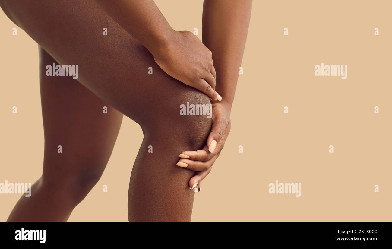 Junge schwarze Frau, die aufgrund von Verletzungen oder rheumatoider Arthritis Schmerzen im Knie spürt Stockfoto