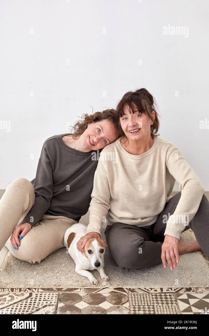 Lächelnde Mutter und Tochter mit Hund zu Hause Stockfoto