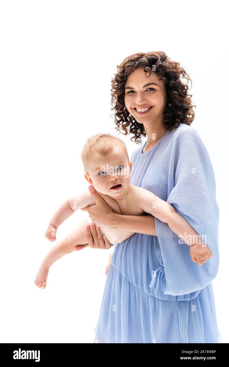 Lächelnde Frau in blauem Kleid hält Baby Mädchen isoliert auf weiß, Stock Bild Stockfoto