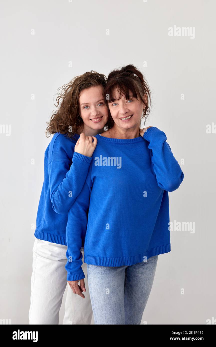 Entzückende Mutter und Tochter in ähnlichen Pullovern im Studio Stockfoto