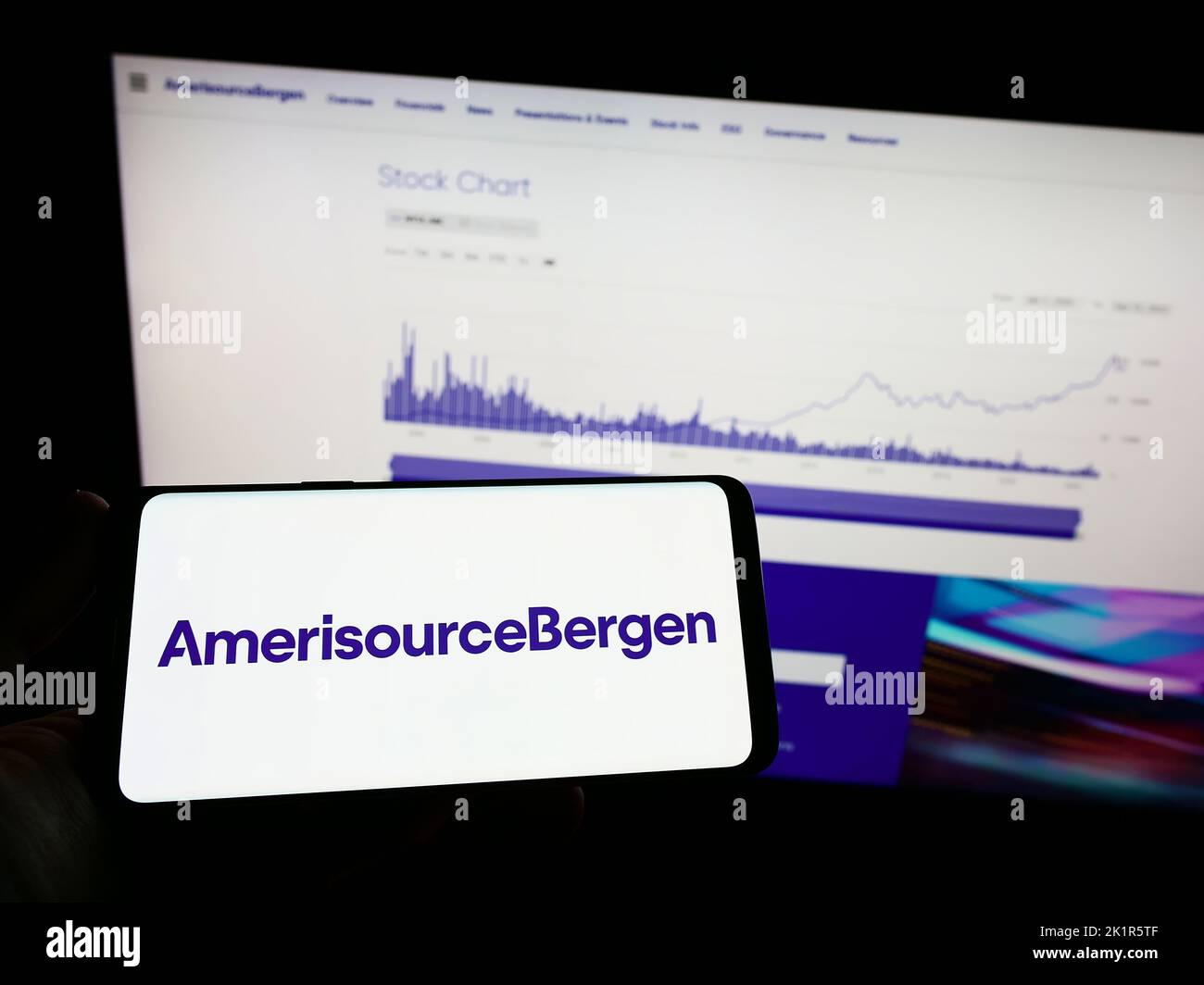 Person, die ein Mobiltelefon mit dem Logo des amerikanischen Pharmaunternehmens AmerisourceBergen Corporation auf dem Bildschirm vor der Webseite hält. Konzentrieren Sie sich auf die Telefonanzeige. Stockfoto