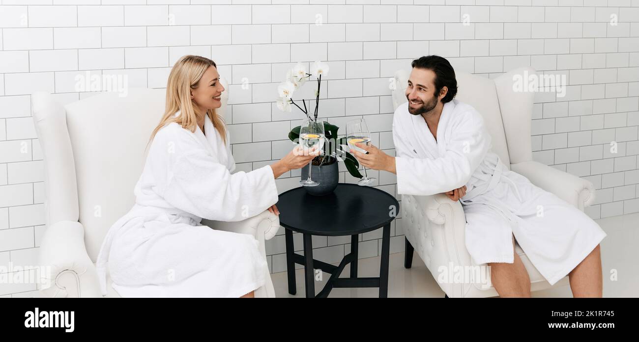 Romantisches Paar trinkt Gesundheitswasser mit limon aus Gläsern, während sie sich in modischem Wellness ausruhen, um ihren Organismus wiederherzustellen Stockfoto