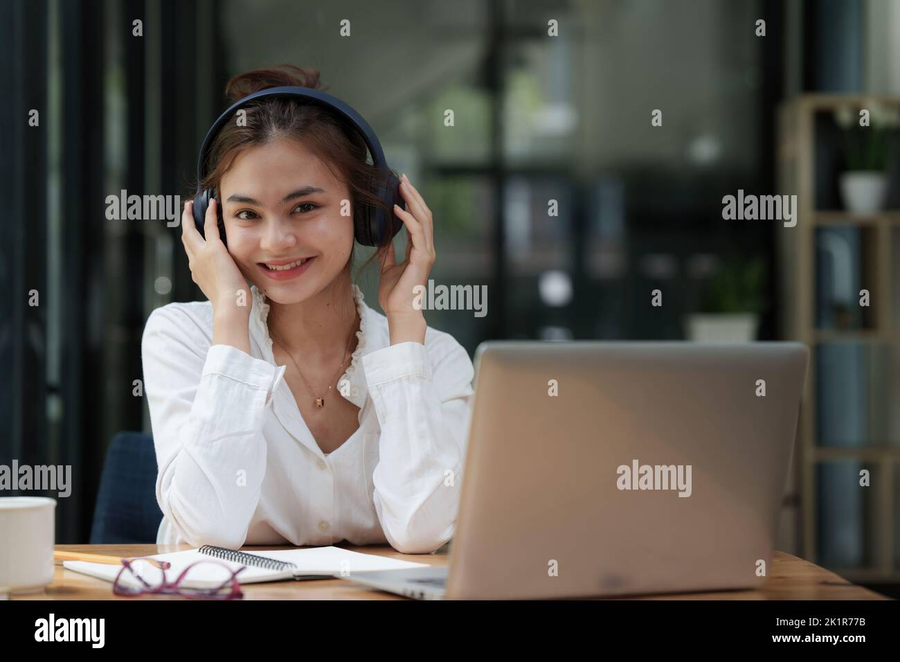 Attraktive lächelnde junge Frau mit Handy und Musik zu Hause hören. Lifestyle-Konzept Stockfoto