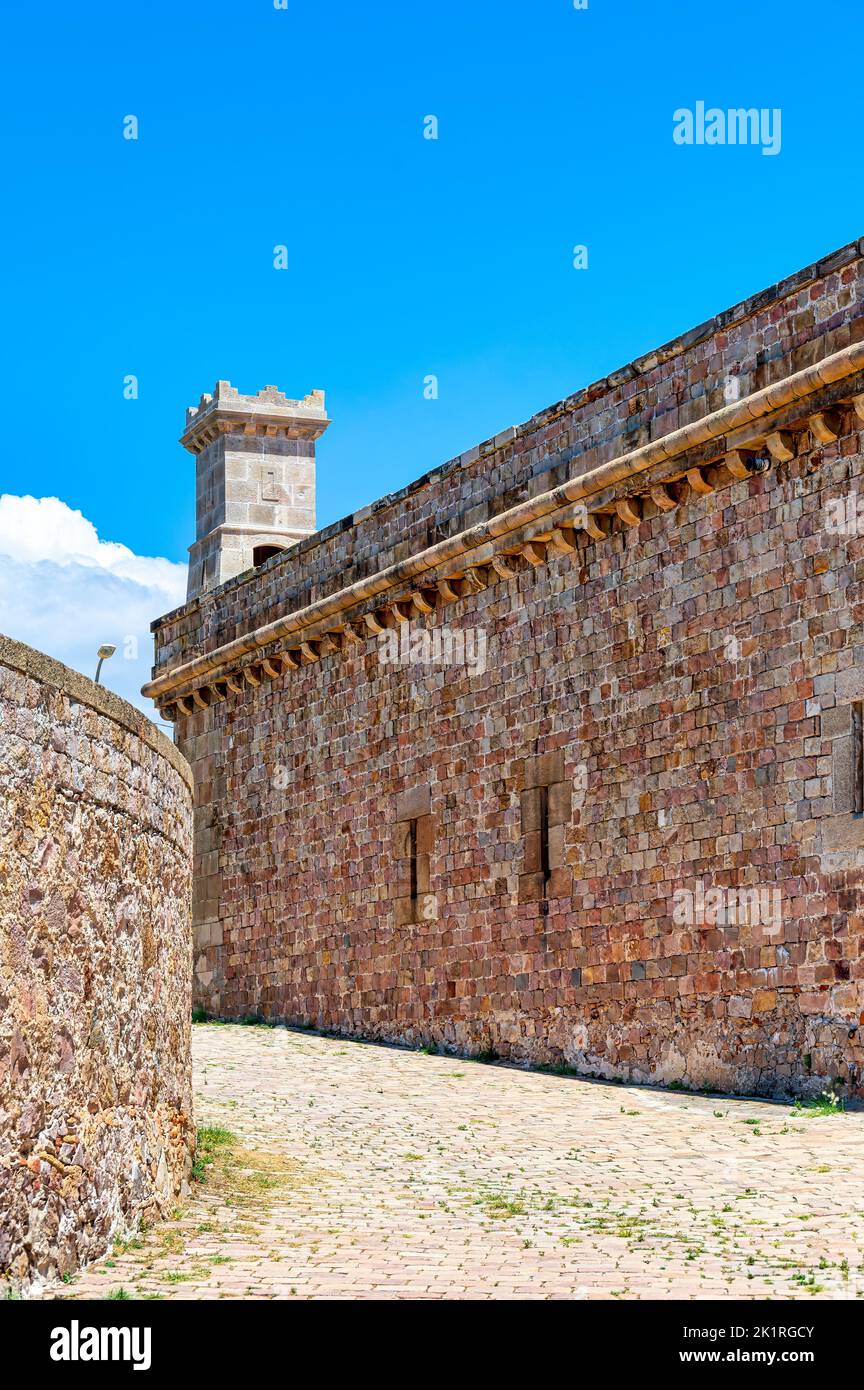 Montjuic Castle. Kopfsteinpflasterstraße und mittelalterliche Steinmauer im Inneren des ehemaligen Militärfests. Stockfoto
