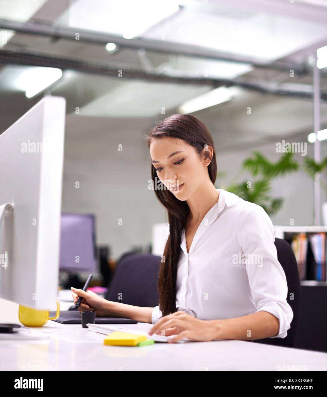 Eine attraktive junge Frau, die an ihrem Schreibtisch arbeitet. Stockfoto