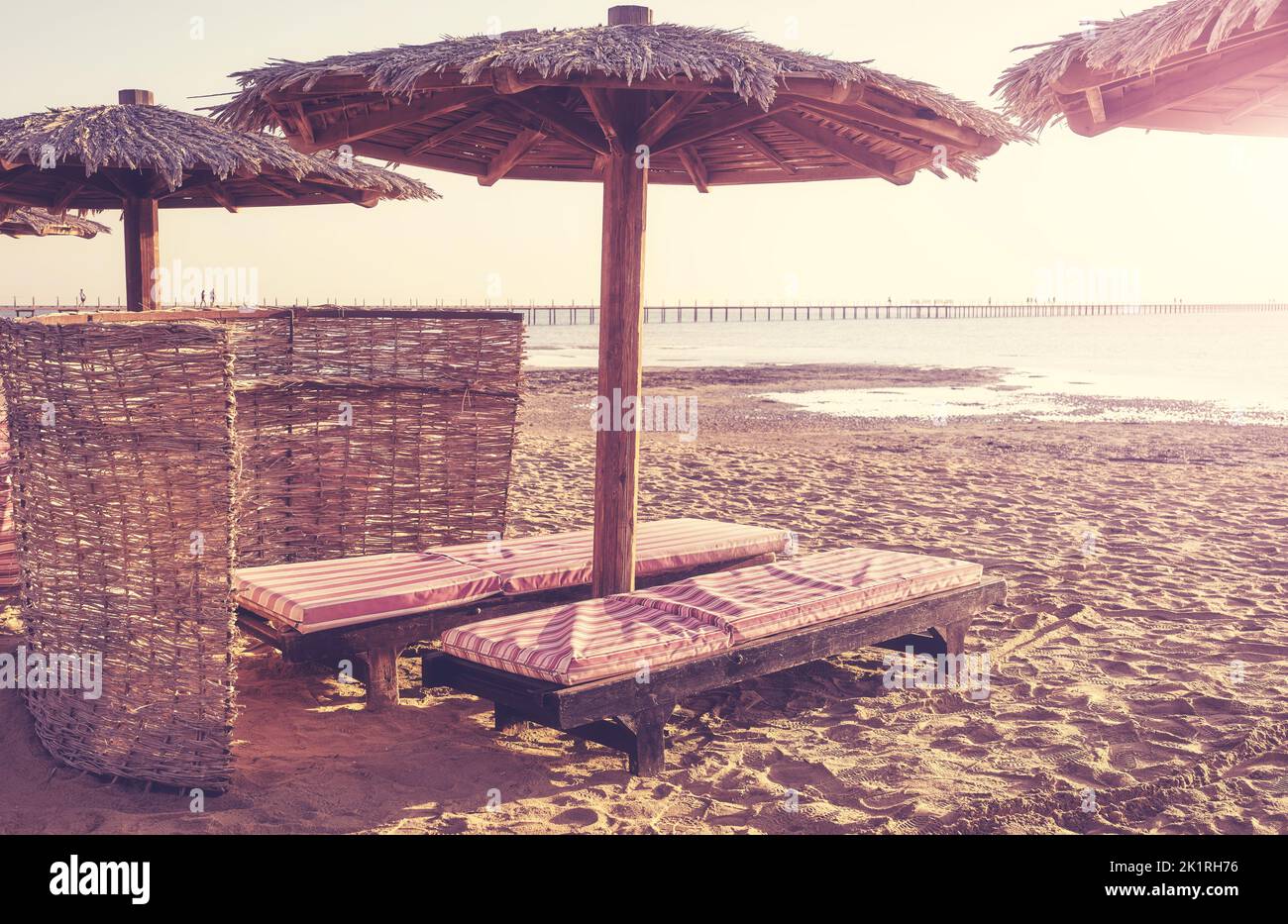 Liegestühle und Sonnenschirme am Strand, Farbtonung angewendet, Sommerurlaubskonzept. Stockfoto