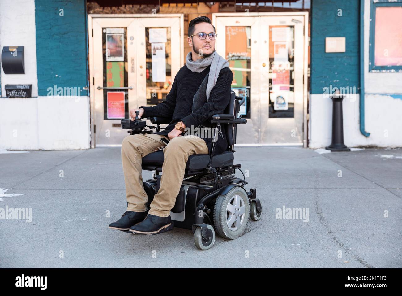 Porträtmann im motorisierten Rollstuhl vor dem Kino Stockfoto