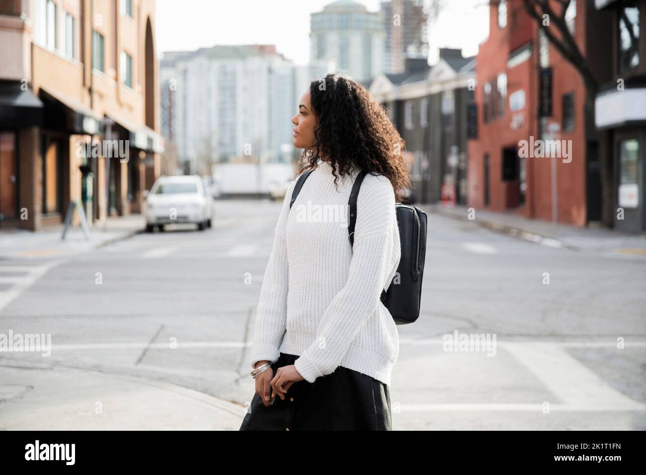 Junge Frau mit Rucksack wartet auf städtische Straßenecke Stockfoto